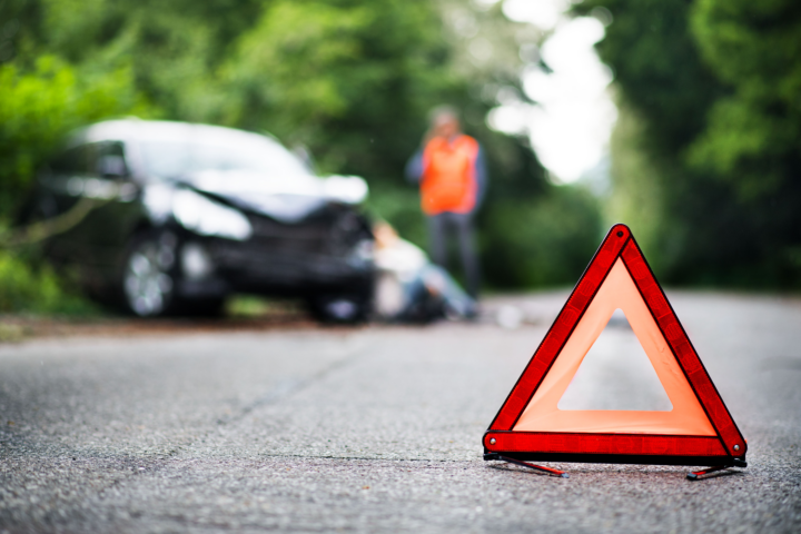 Eine Frau sichert die Unfallstelle ab und setzt den Notruf ab.